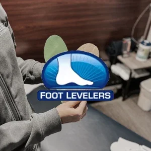 A person holding custom orthotic insoles with the Foot Levelers logo displayed prominently.